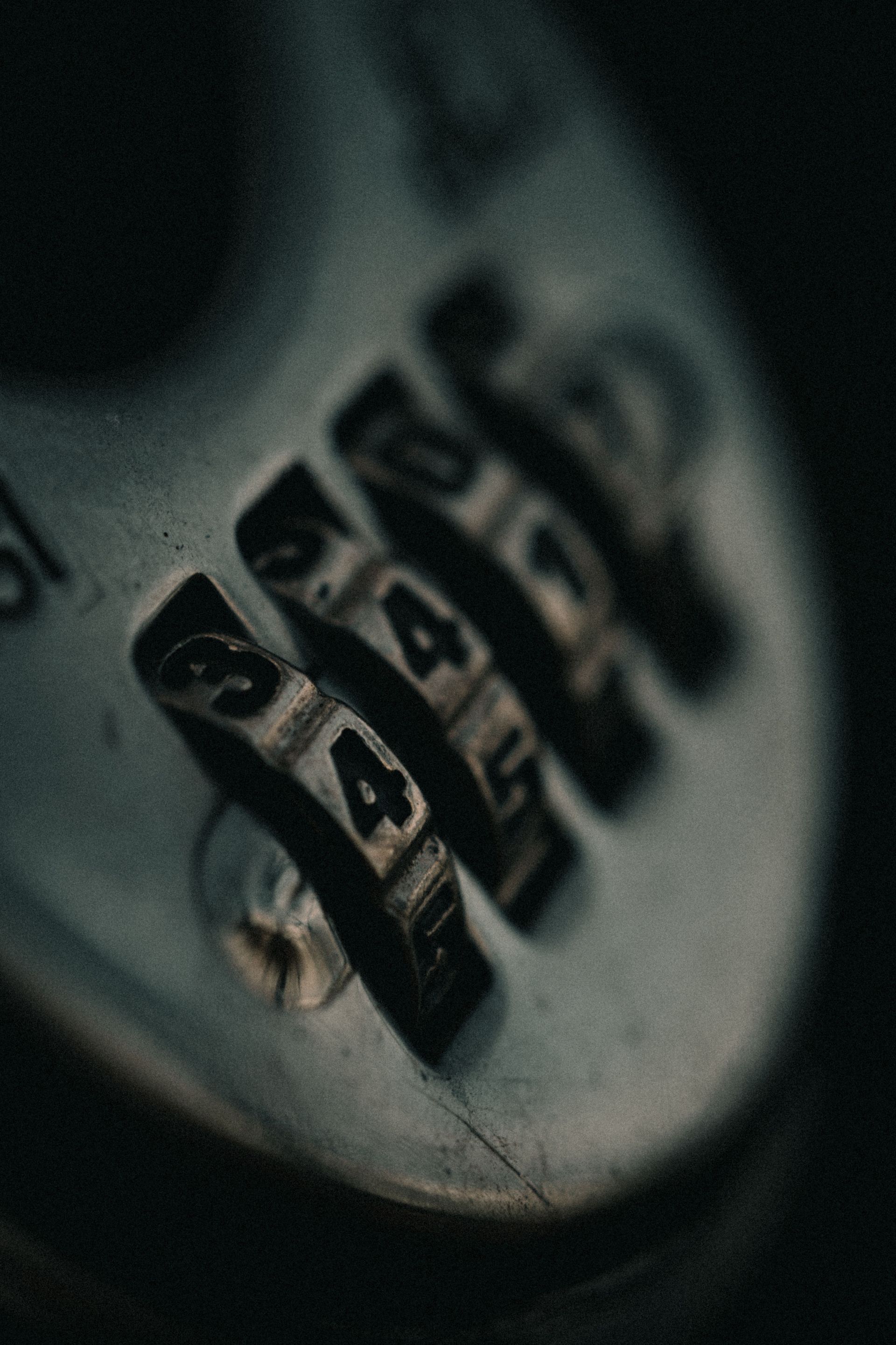 Close-up of a silver combination lock with black number dials on a dark background