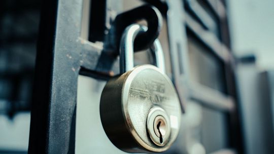 Close-up of a silver padlock on a black metal gate