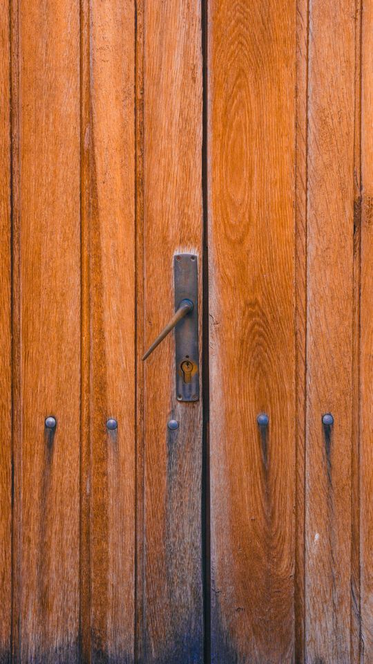Wooden double doors with a dark metal latch and vertical weathered planks