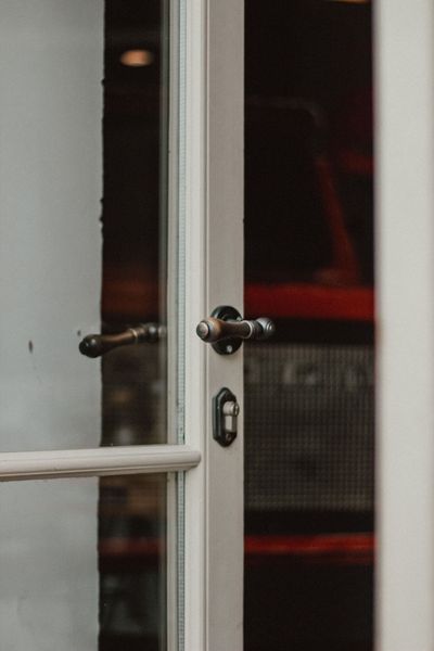 Open glass door with a metal handle, showing a dim red-lit interior behind it