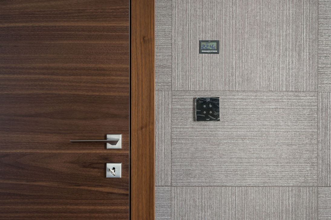 Modern interior wall with wood paneling, textured wallpaper, and two light switches.