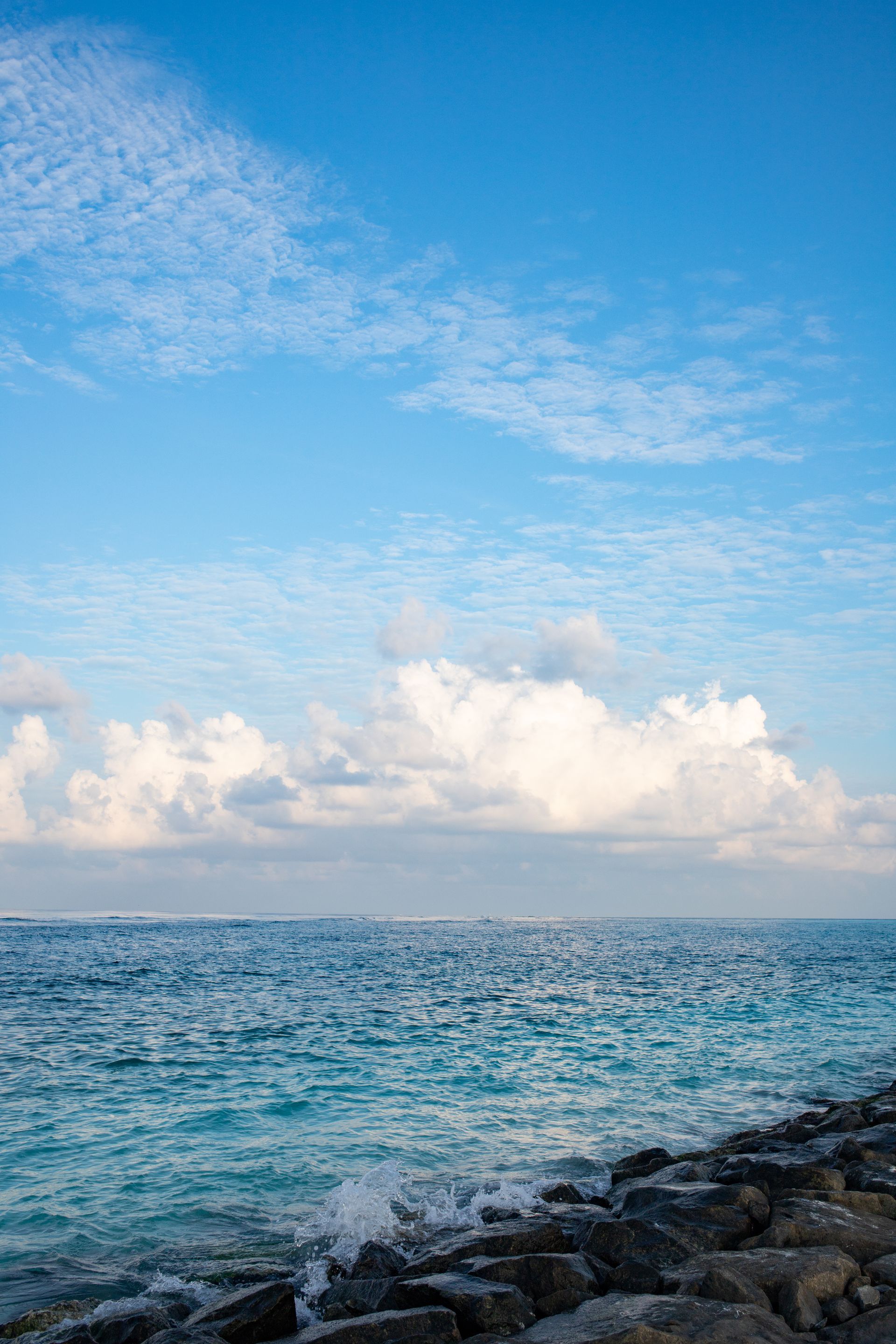 A large body of water with a blue sky and clouds in the background.