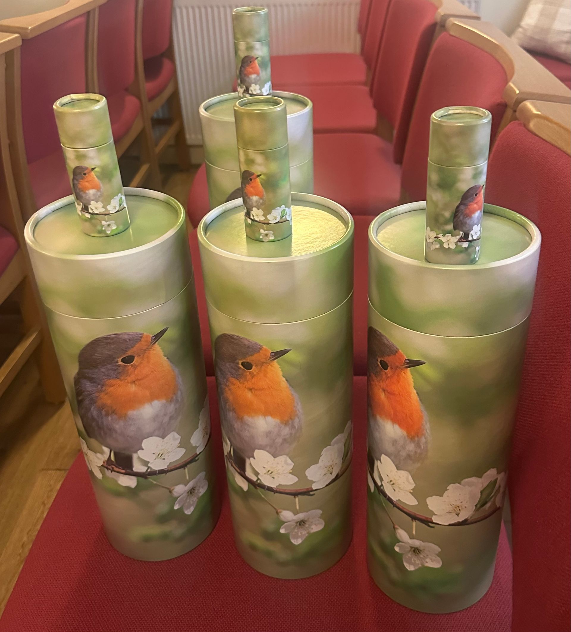 Five painted green glass bottles with bird and flower designs arranged on a red chair