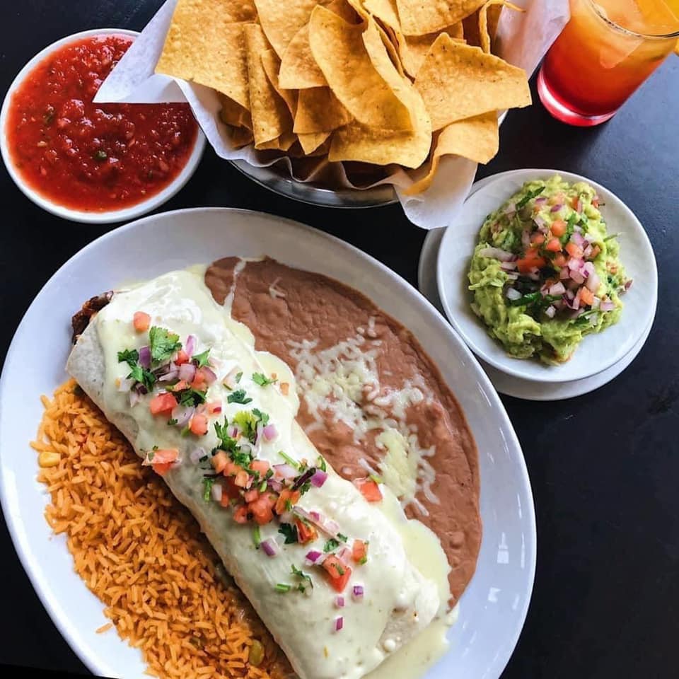Burrito, rice, beans, chips, salsa, and guacamole on a table. Mexican food.