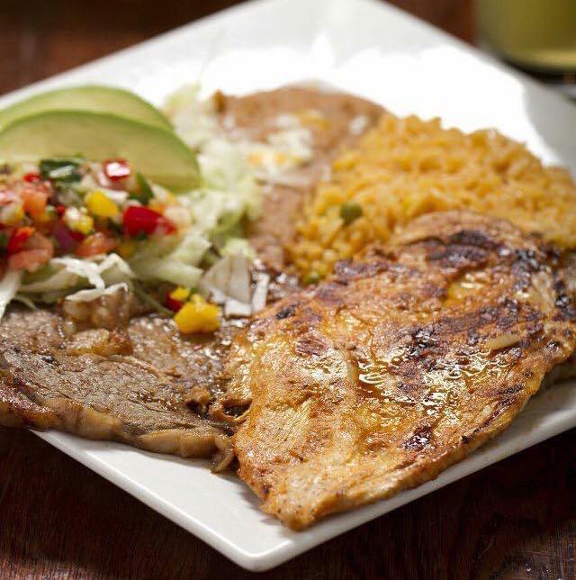 Plate of grilled meat, rice, beans, salsa, avocado slices, and lettuce.