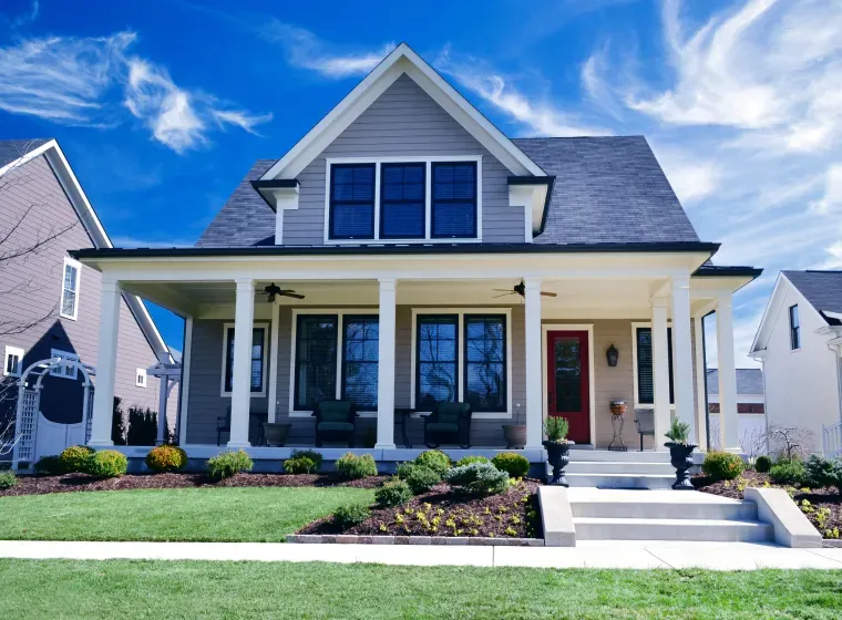 A large house with a large porch and a red door