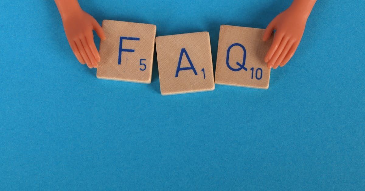 A person is holding scrabble tiles that spell out the word faq.