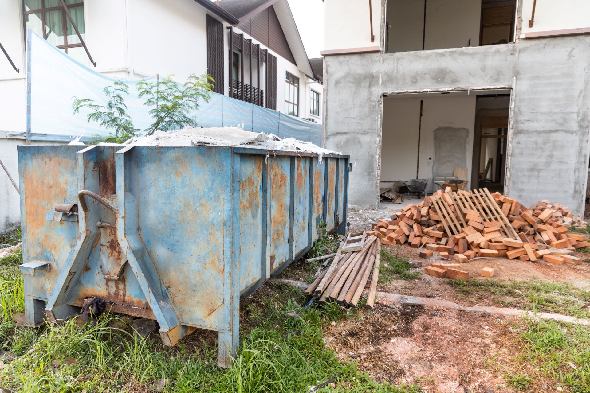 A dumpster is sitting in front of a building under construction.