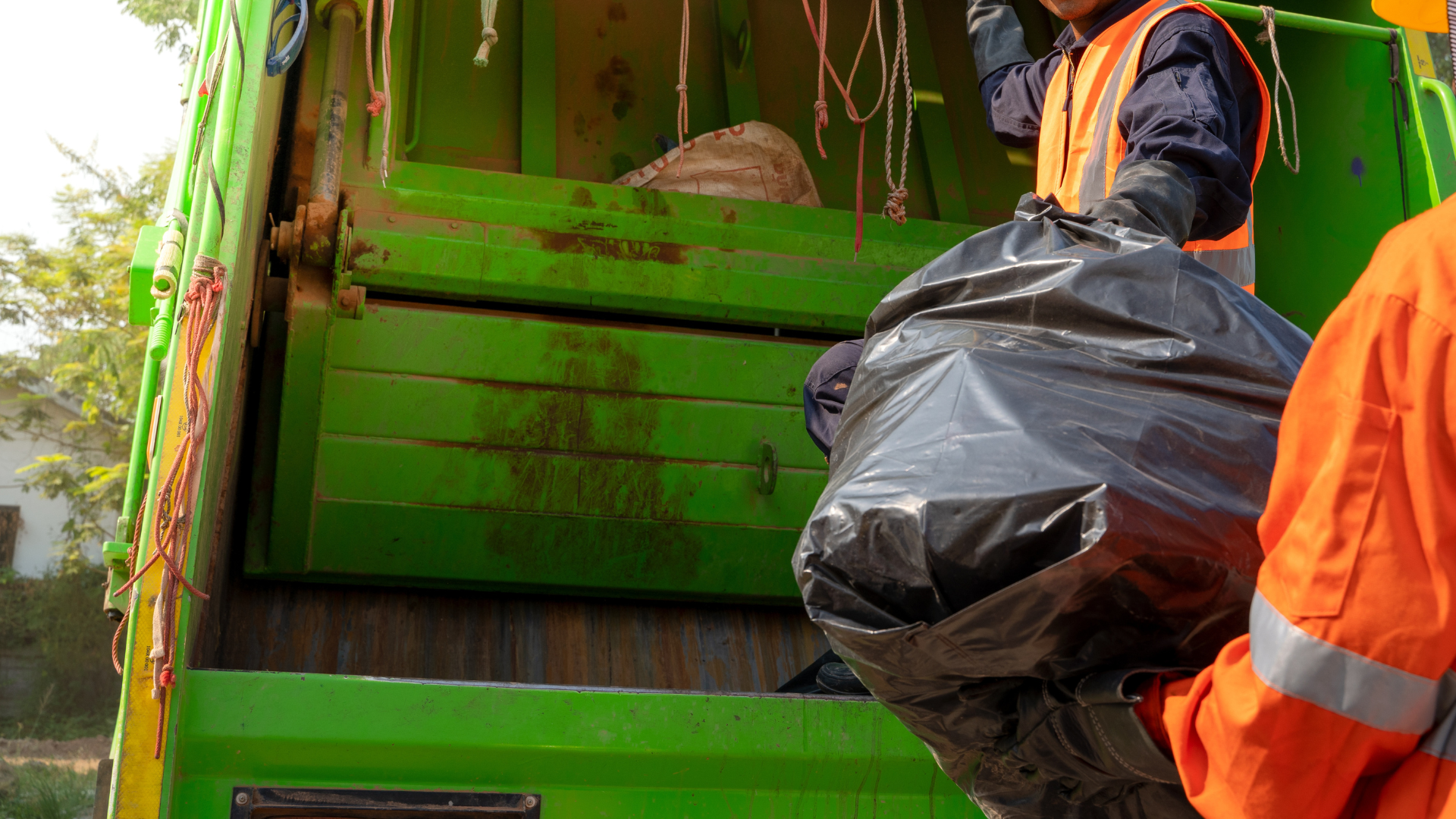 A man is loading garbage into a garbage truck.