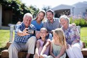Family sitting together and smiling outdoors in a sunny garden