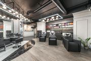 Modern salon interior with black styling chairs, mirrors, and gray wood flooring