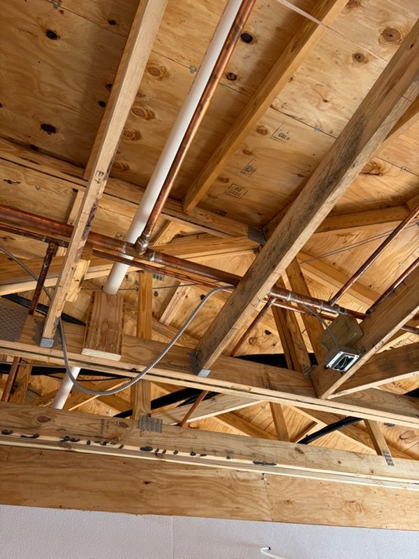Exposed wooden roof trusses and beams inside an unfinished attic or ceiling space.