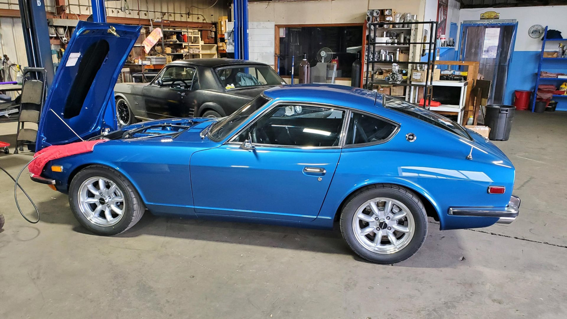A blue sports car with the hood up is parked in a garage. | Kirk's Radiator & Auto A/C Inc.