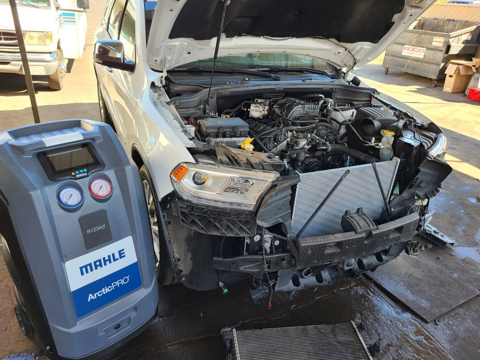 A white car with the hood up and a machine next to it. | Kirk's Radiator & Auto A/C Inc.