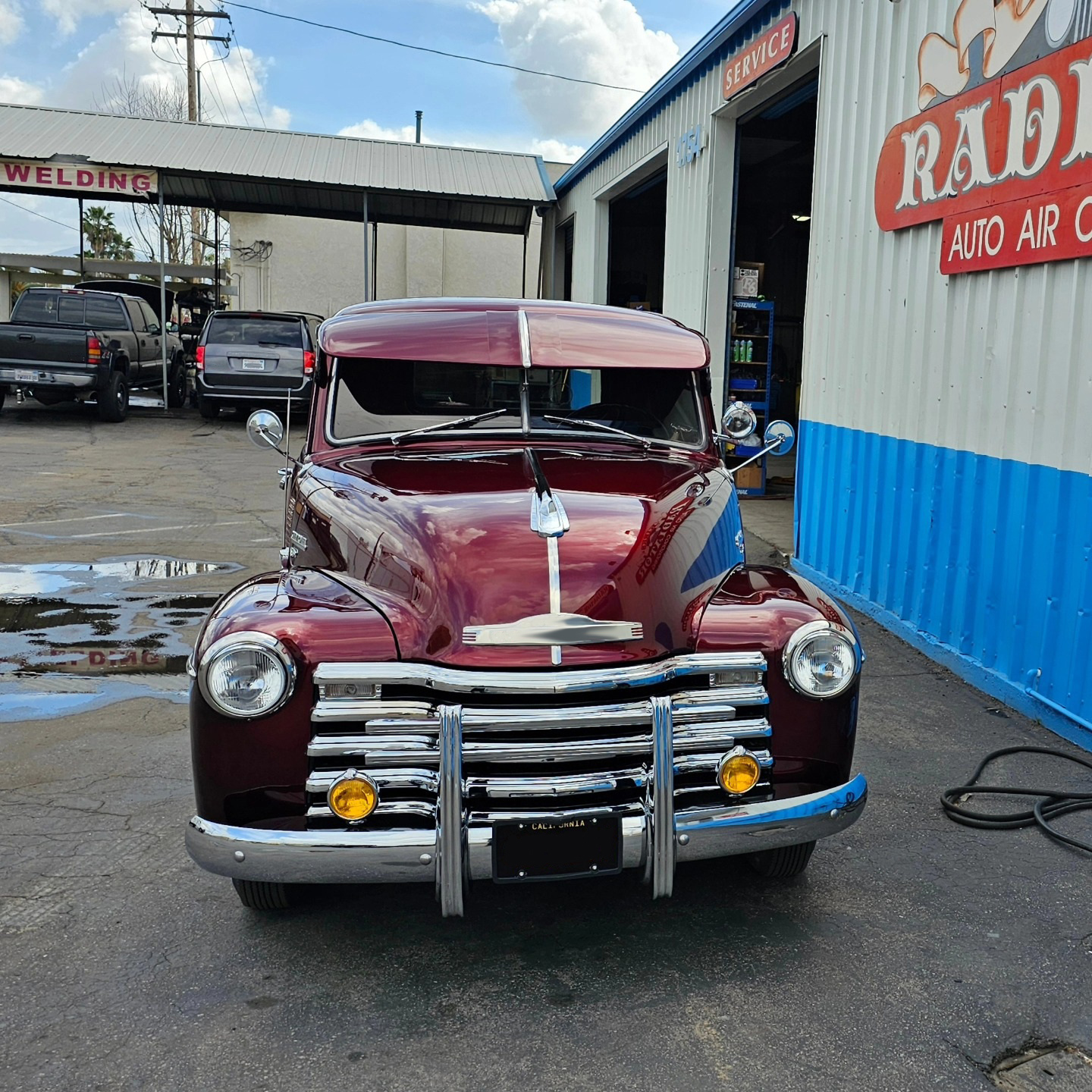 A red car is parked in front of a building | Kirk's Radiator & Auto A/C Inc.