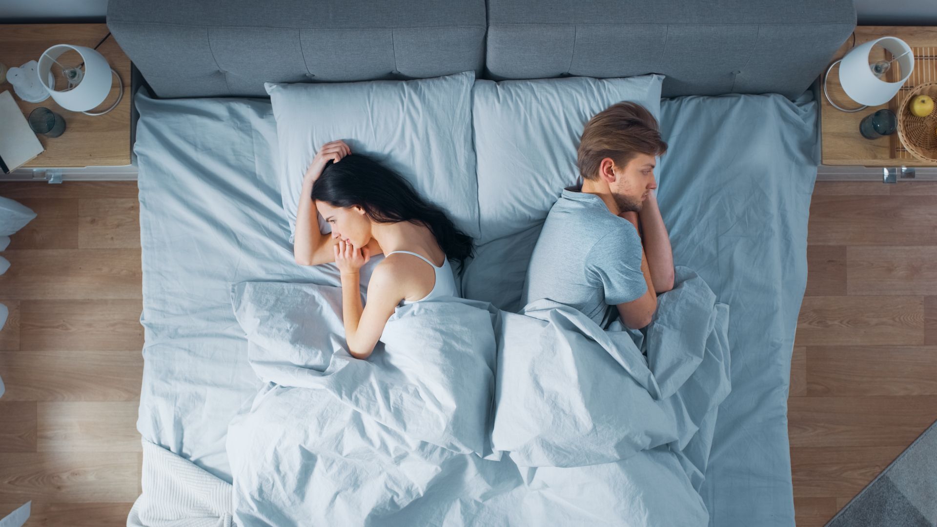 Un uomo e una donna sono sdraiati schiena contro schiena su un letto.
