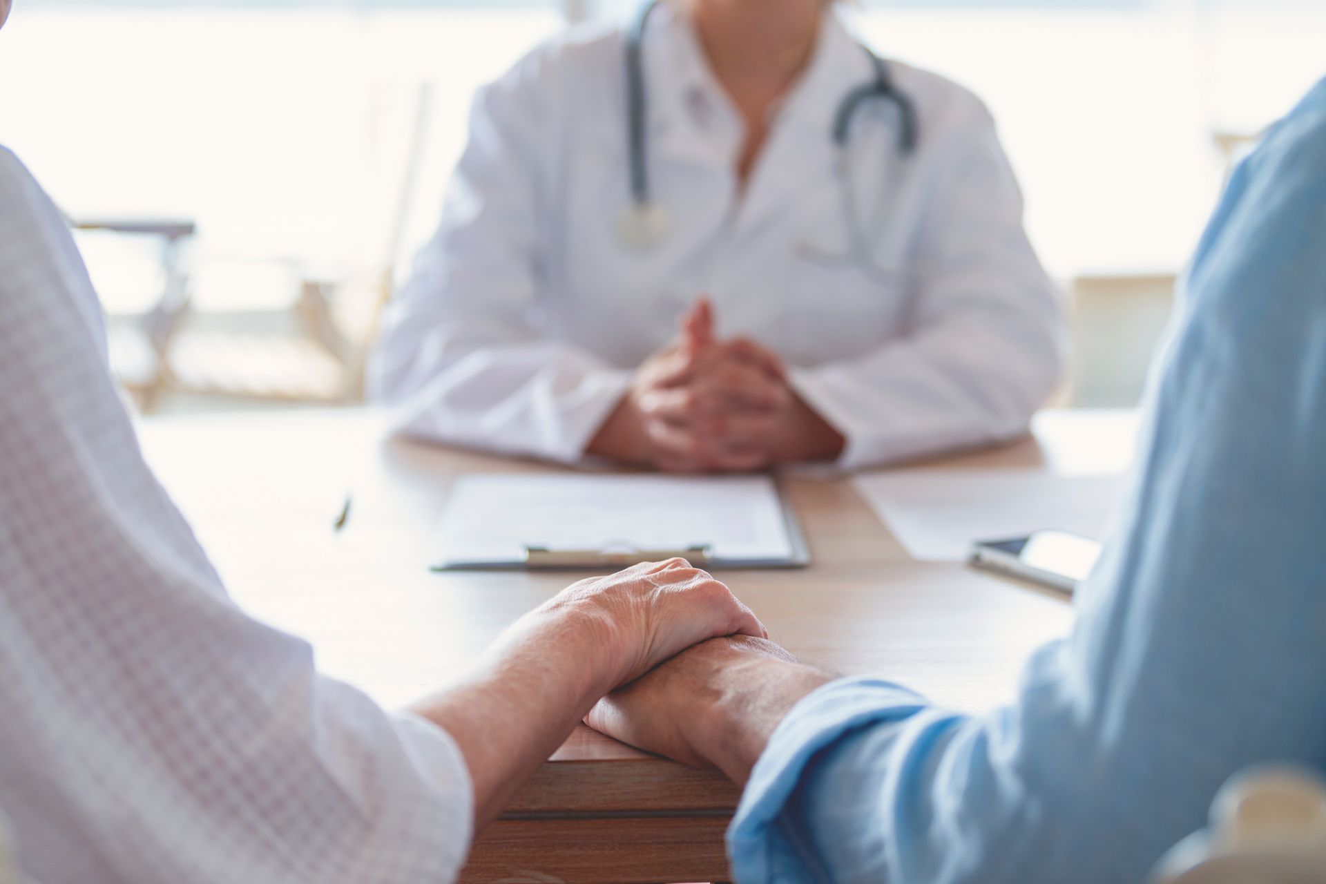 Un medico tiene la mano di un paziente mentre è seduto al tavolo.