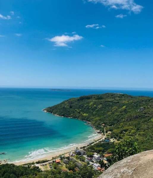 Uma vista de uma praia a partir de uma falésia com vista para o oceano.