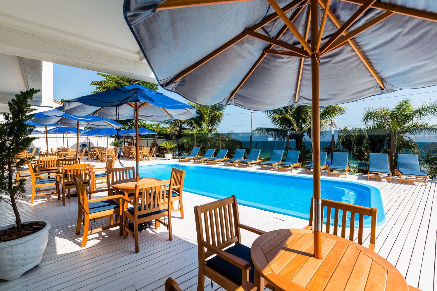 Uma piscina com mesas e cadeiras e guarda-sóis ao redor
