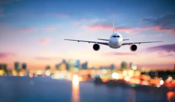 Airplane approaching runway at dusk with city lights blurred in the background