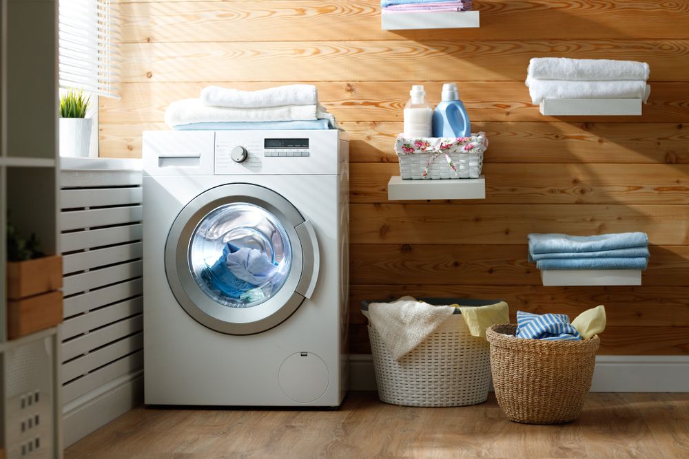 A Washing Machine in a Laundry Room Next to a Basket of Clothes — Byron Bay Carpentry and Construction In Suffolk Park, NSW