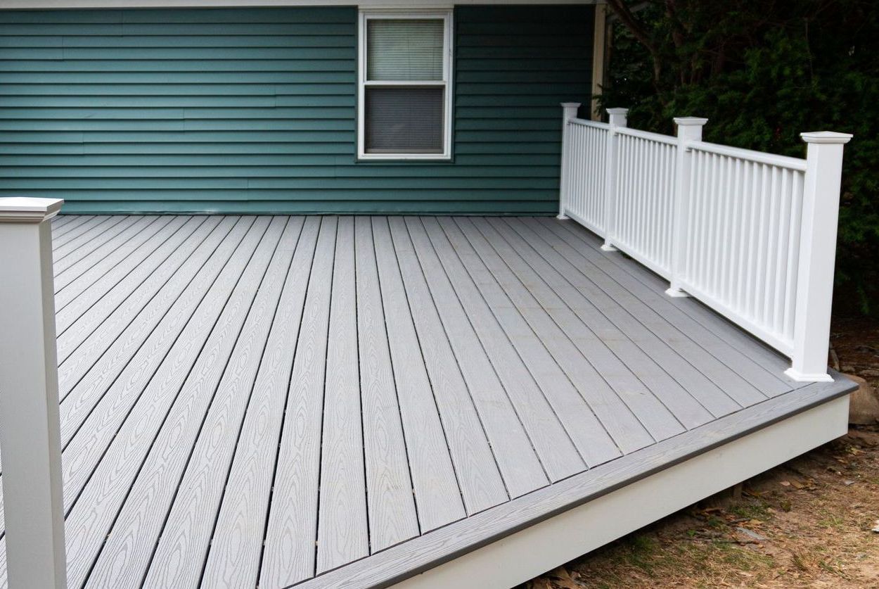 A Gray Deck With a White Railing is in Front of a Green House — Byron Bay Carpentry and Construction In Mullumbimby, NSW