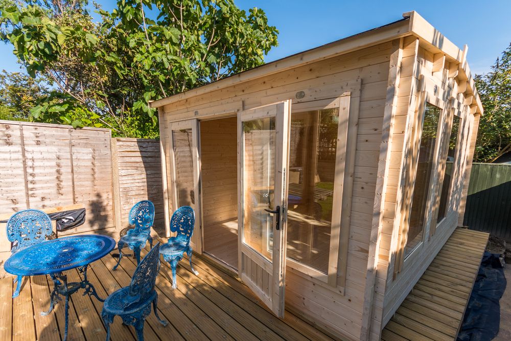A wooden shed is newly built surrounded by deck and outdoor table and chairs — Byron Bay Carpentry and Construction In Ballina, NSW