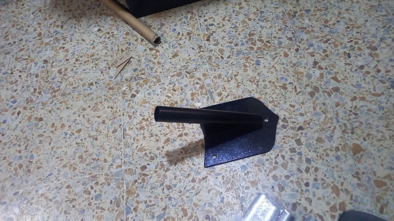 Black dustpan with handle on a speckled floor next to a wooden stick