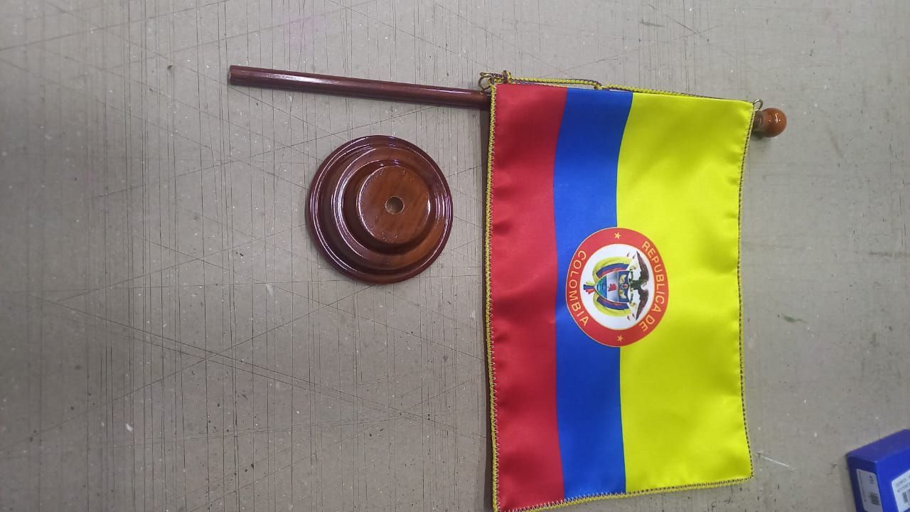 Small desk flag with red, blue, and yellow stripes beside a round wooden wall plaque.