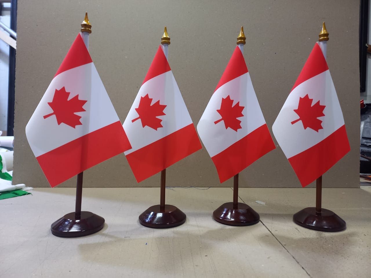 Four small Canadian flags on stands lined up on a table