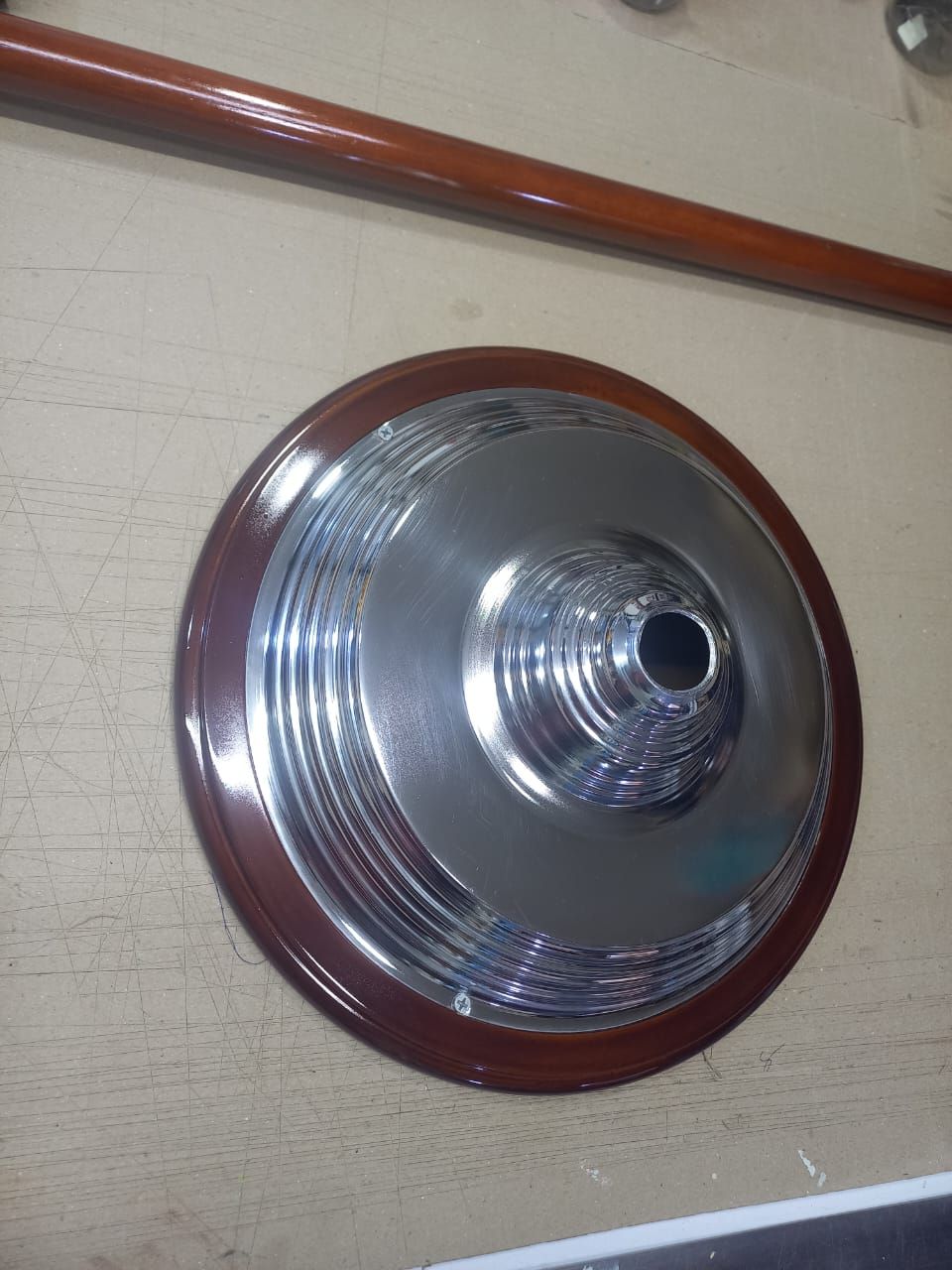 Round silver wall-mounted light with a dark red rim on a beige wall
