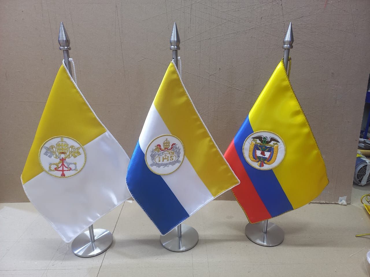 Three small desk flags: Vatican, Ecuador, and Colombia, displayed on stands.