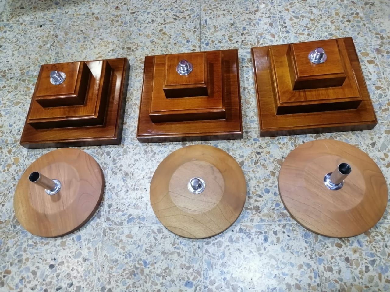 Seis bloques de madera con pomos metálicos dispuestos en dos filas sobre una superficie moteada.