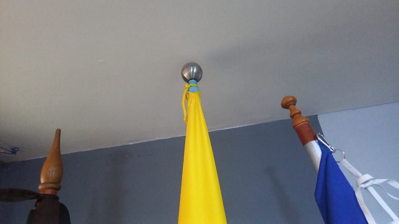 Tres banderas colgadas del techo: amarilla en el centro, azul a la derecha y marrón a la izquierda.