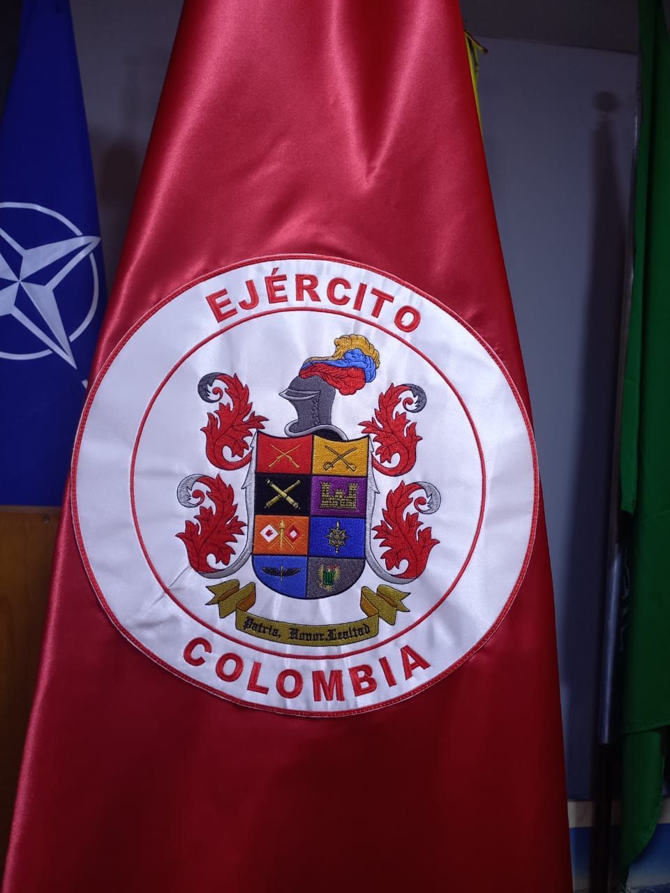 Bandera del Ejército colombiano con tela roja y el escudo nacional en un círculo blanco.