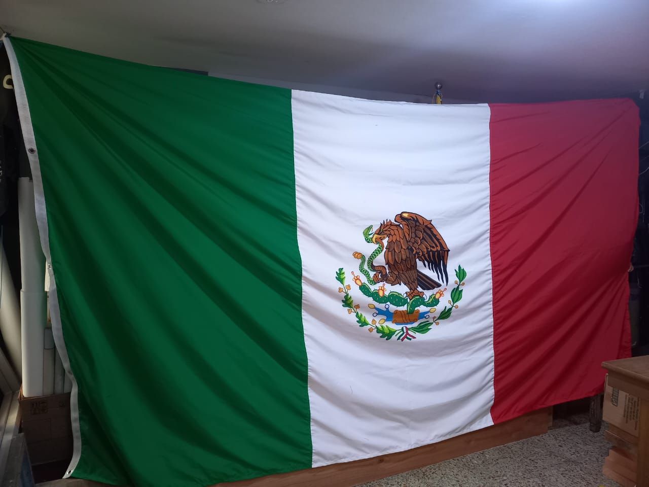 Bandera mexicana colgada en el interior, con franjas verticales verdes, blancas y rojas y el emblema nacional centrado.