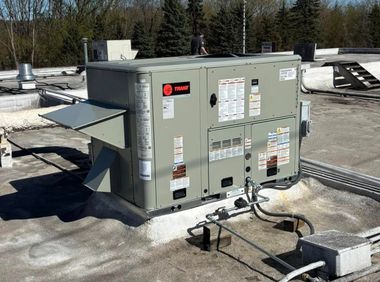 Outdoor industrial HVAC unit on a rooftop with ducts and snow around it