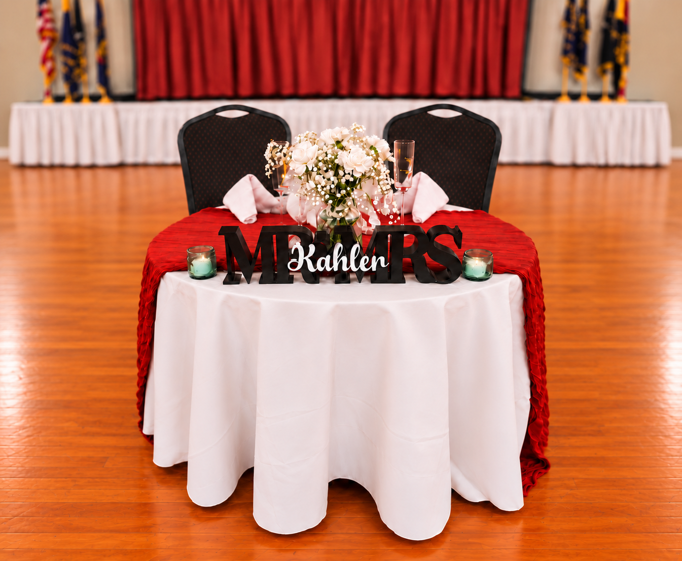 Banquet hall with round tables set for an event, white and red tablecloths, and chairs arranged around the room
