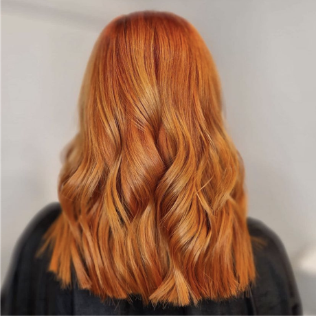 Back view of shoulder-length wavy copper hair on a person in a dark top