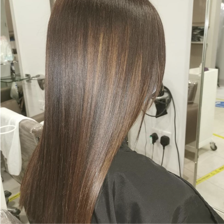 Long, straight brown hair with subtle highlights in a salon mirror