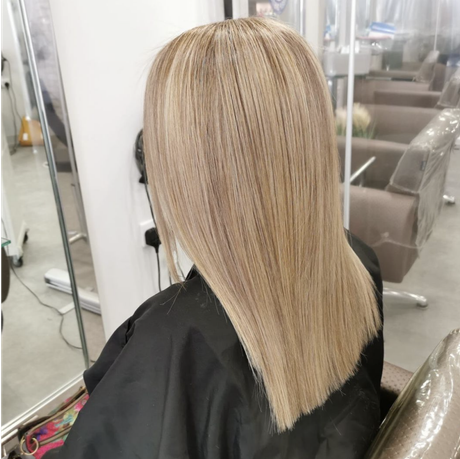 Blonde hair styled straight and sleek in a salon chair, shown from the back.