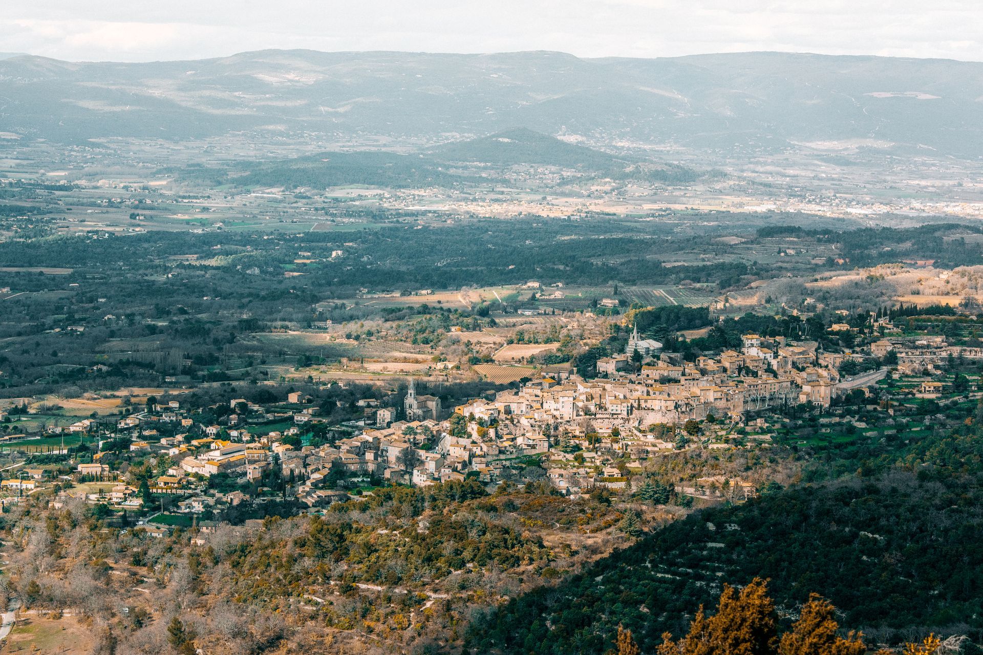 Vue panoramique d'une ville et de collines verdoyantes sous un ciel brumeux