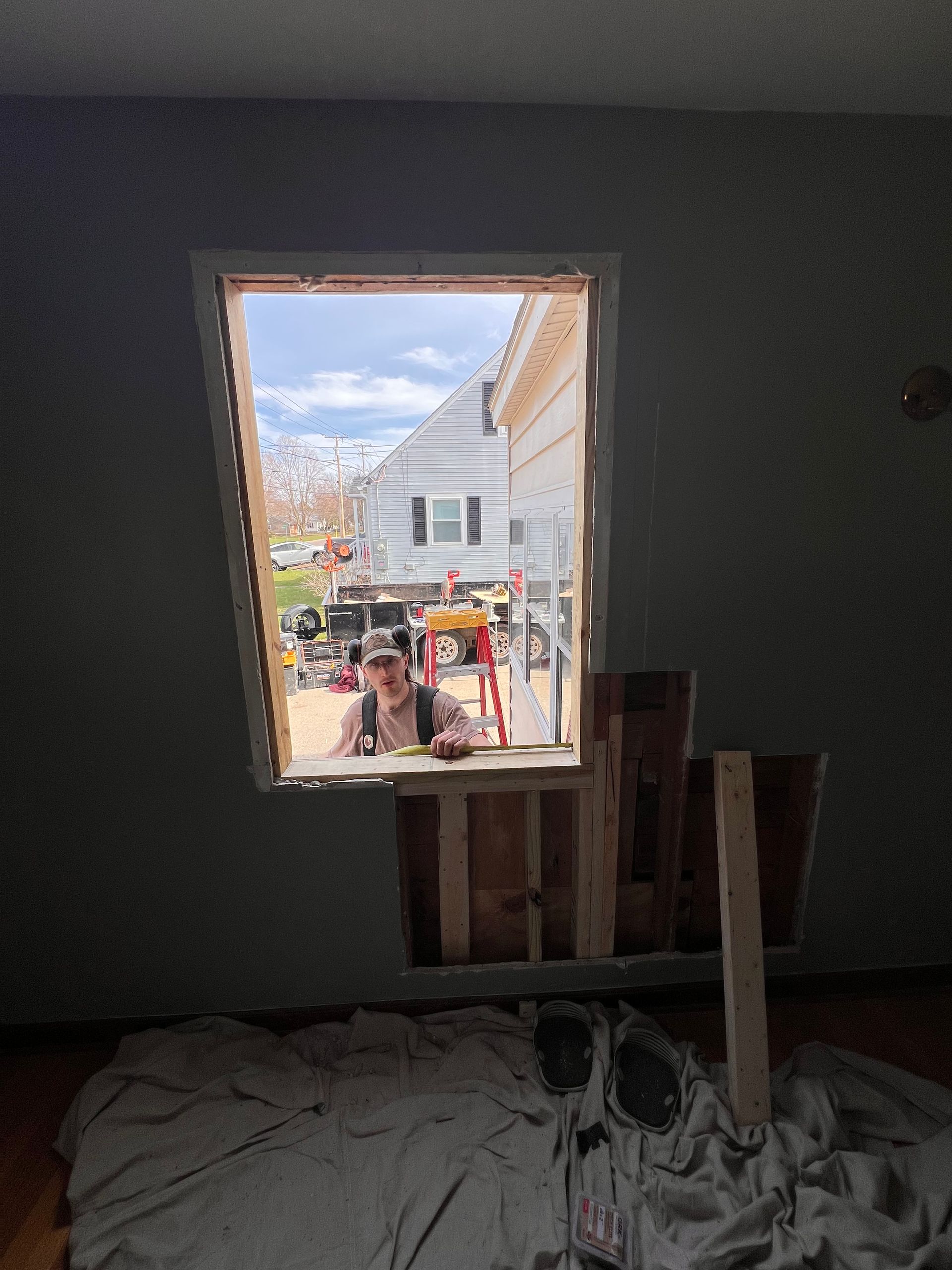 Unfinished room with a window opening to a street view and construction materials inside.