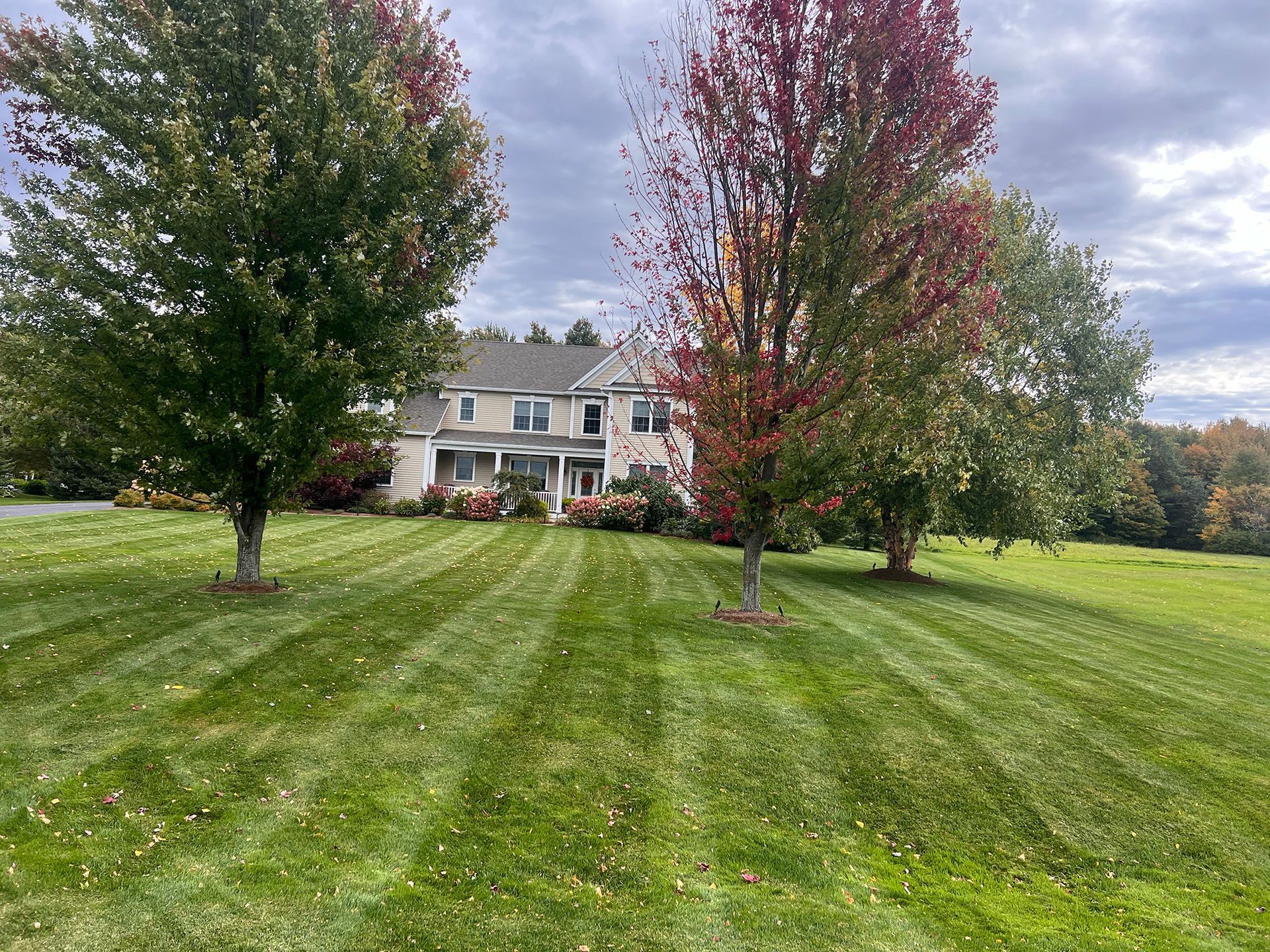 Lawn care technician mowing a Vermont residential property