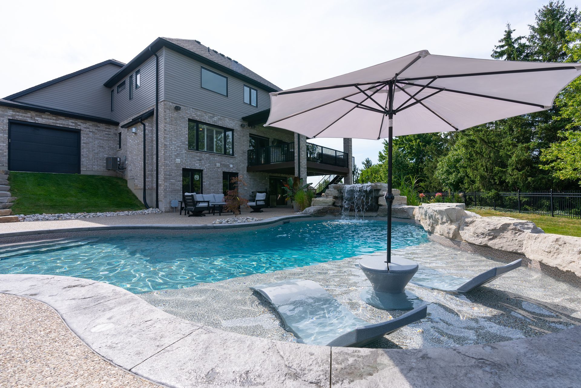 Modern house with a backyard pool and large patio umbrella on a sunny day