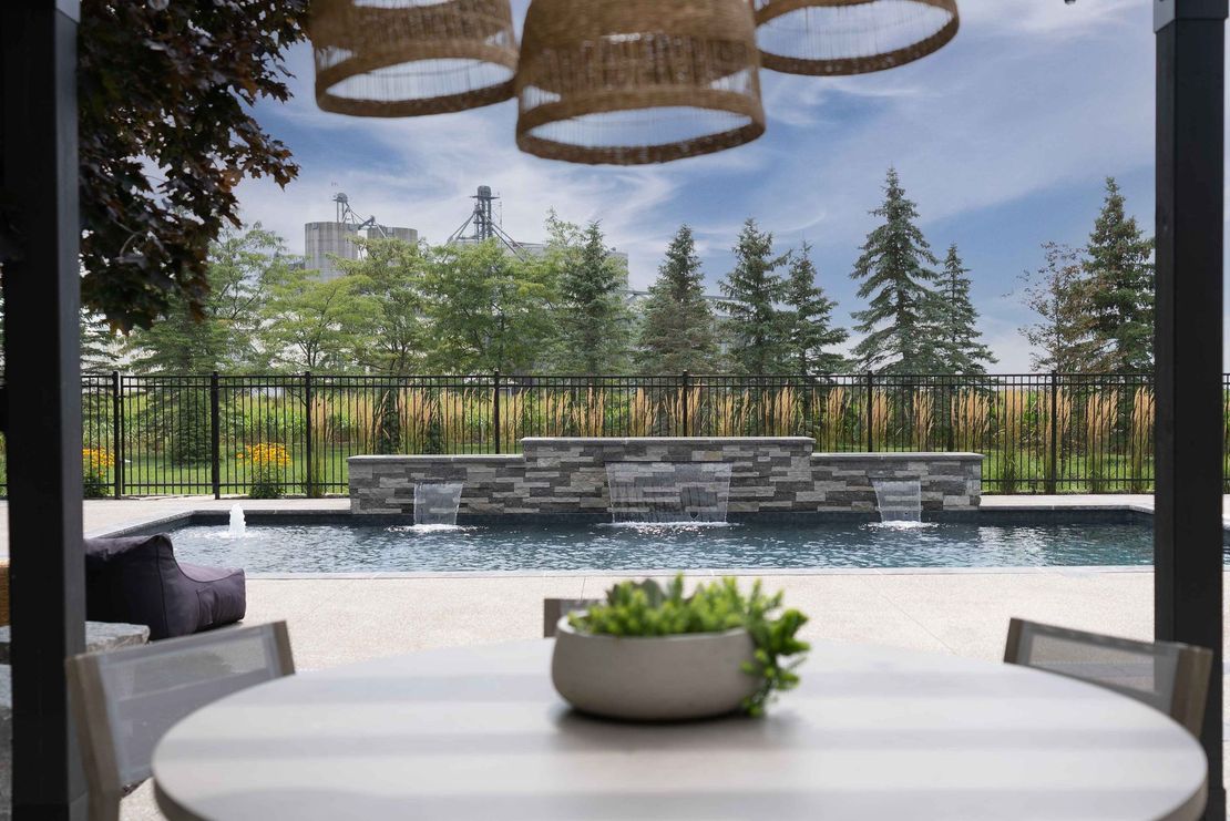 Backyard pool beside a modern house with a covered patio and stone steps