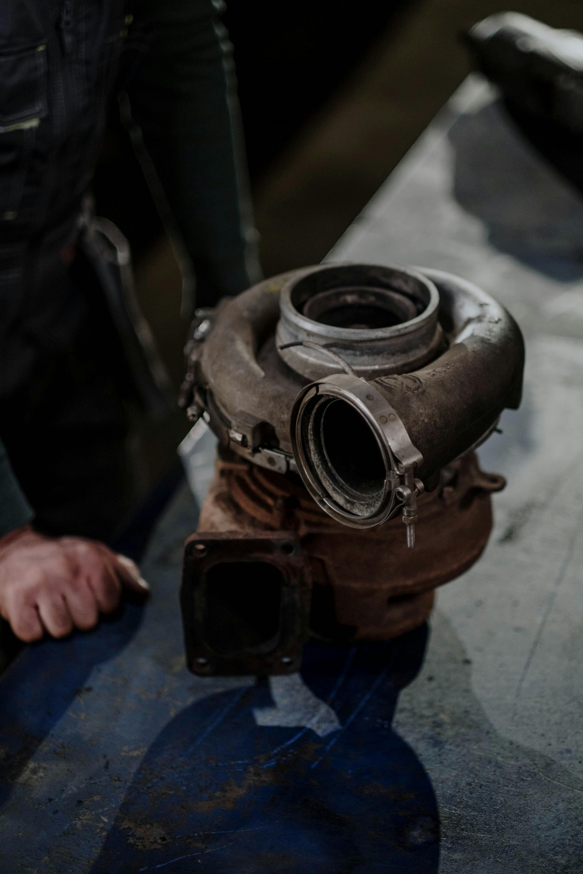 A close up of a person holding a turbocharger on a table.