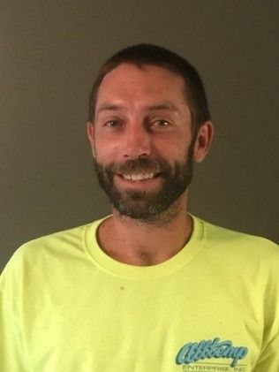 Man with beard in yellow shirt smiles.