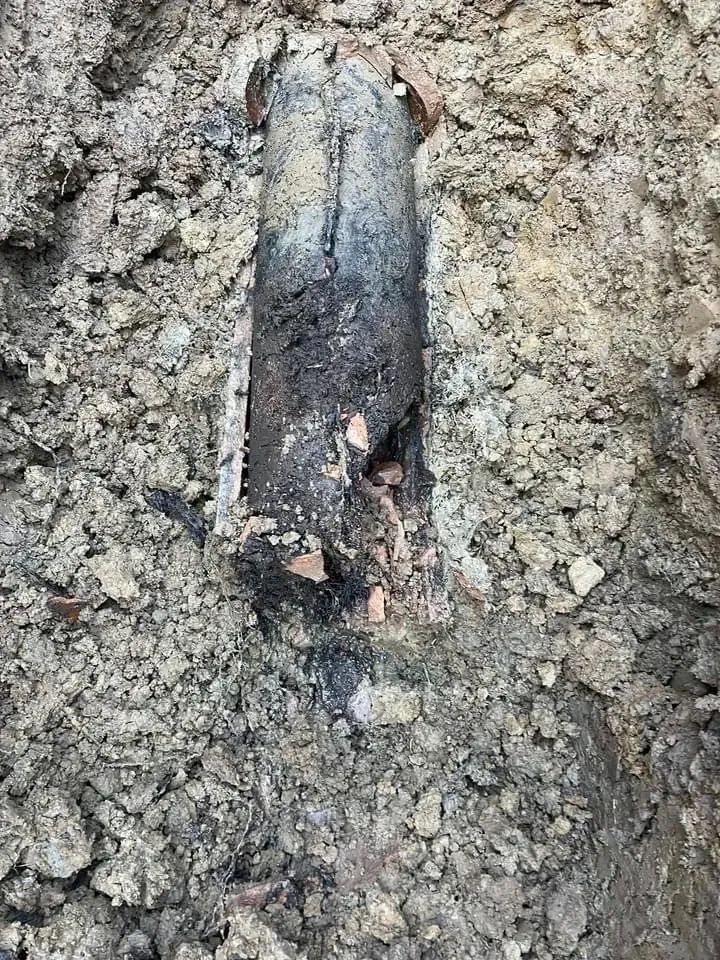 Damaged underground pipe section in soil.