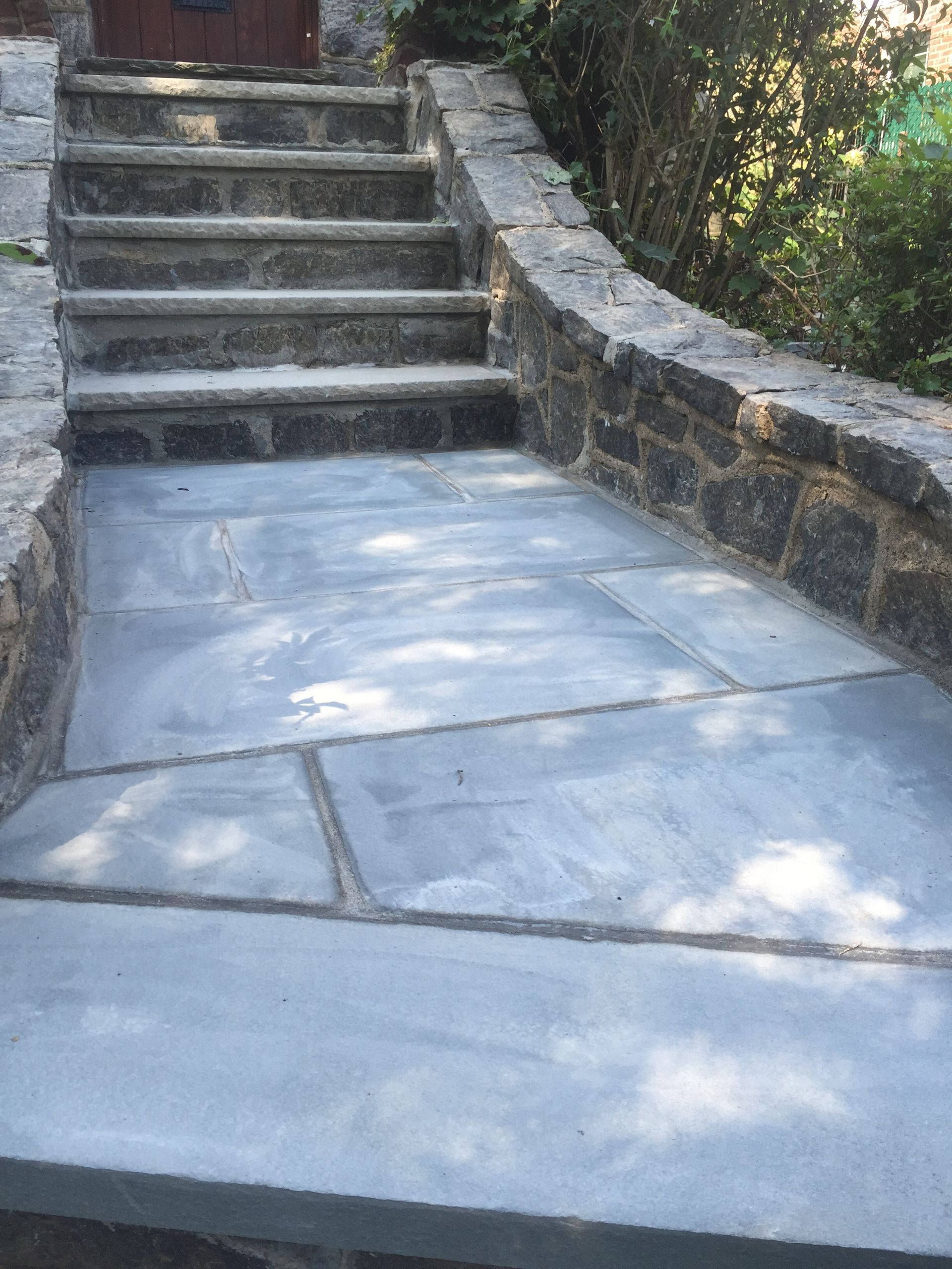 Stone steps and a curved walkway with a smooth concrete ramp beside them outdoors.